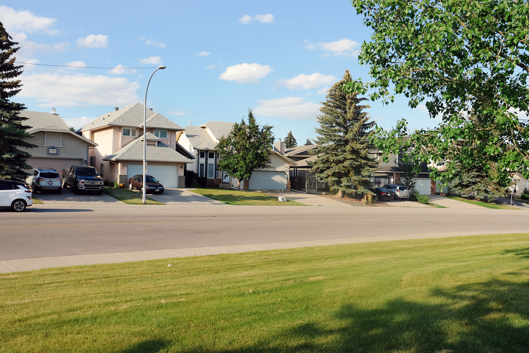 A residential street with single family homes for sale in the community of Riverbend, Calgary, AB
