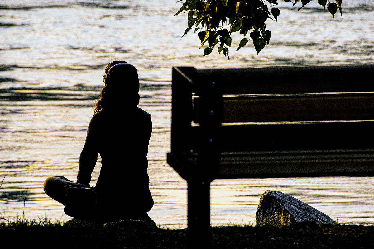 Woman meditating next to the Bow River in Calgary, Alberta, Canada